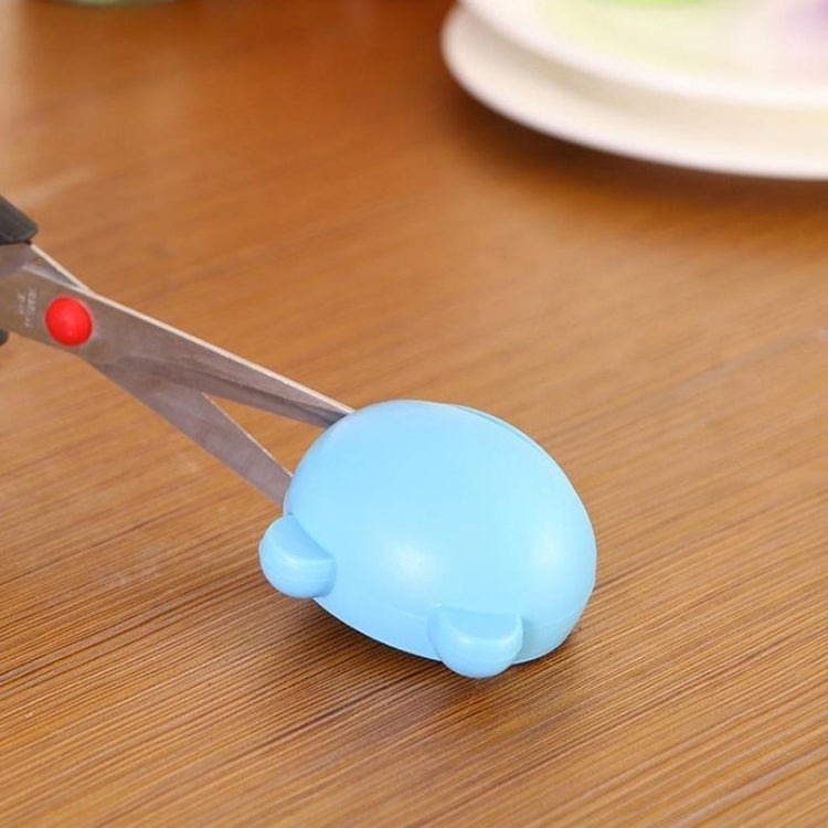 Blue handheld knife sharpener resting on wood with sharpening slot