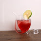 Clear glass juice mug with straw, filled with red drink and lime wedge