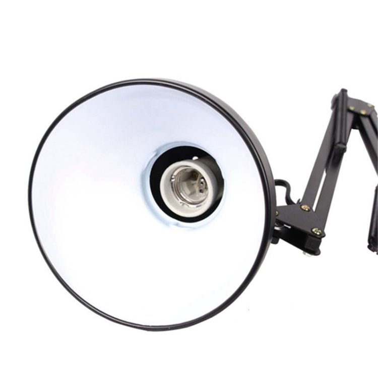 Close-up of round light head on black swing arm desk lamp