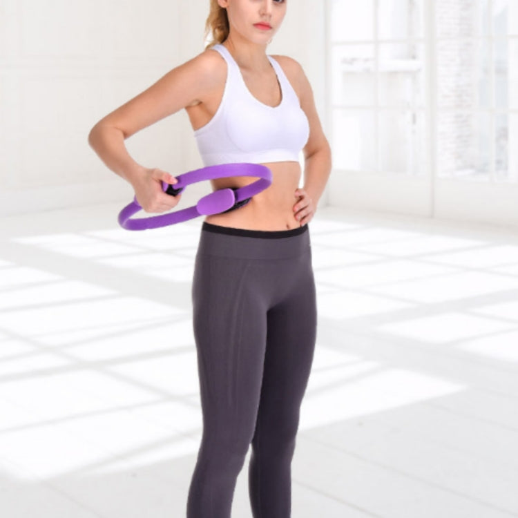 Purple Pilates ring with foam pads, held at waist for training
