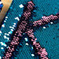 Close-up of lake blue and pink sequin scales with dark sequin letter detail