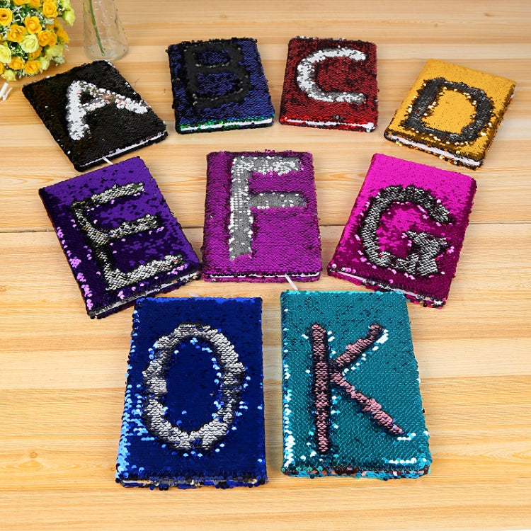 Assorted sequin flip letter notebooks on table, including lake blue K design