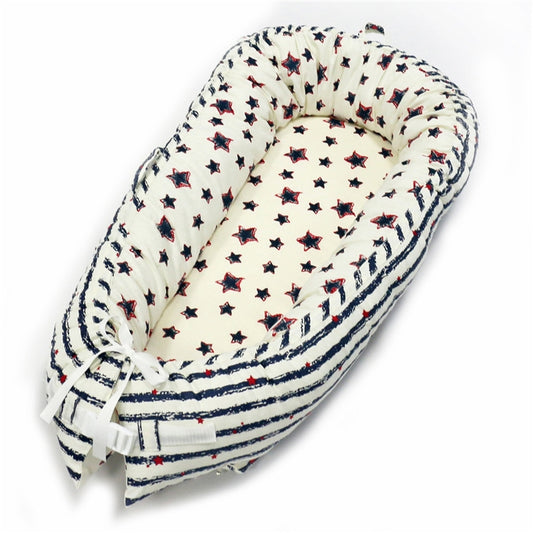Cream baby nest with navy star print and striped edging, tie-back ends