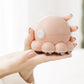 Pink octopus shoulder massager held in hands, round control pad on top