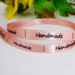 Pink satin "Handmade" ribbon detail with dotted lines along the edge