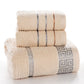 Stacked light beige cotton bath towels with blue and orange stripes and Greek key trim