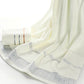 Folded light beige towel with subtle Greek border and pale stripe band detail