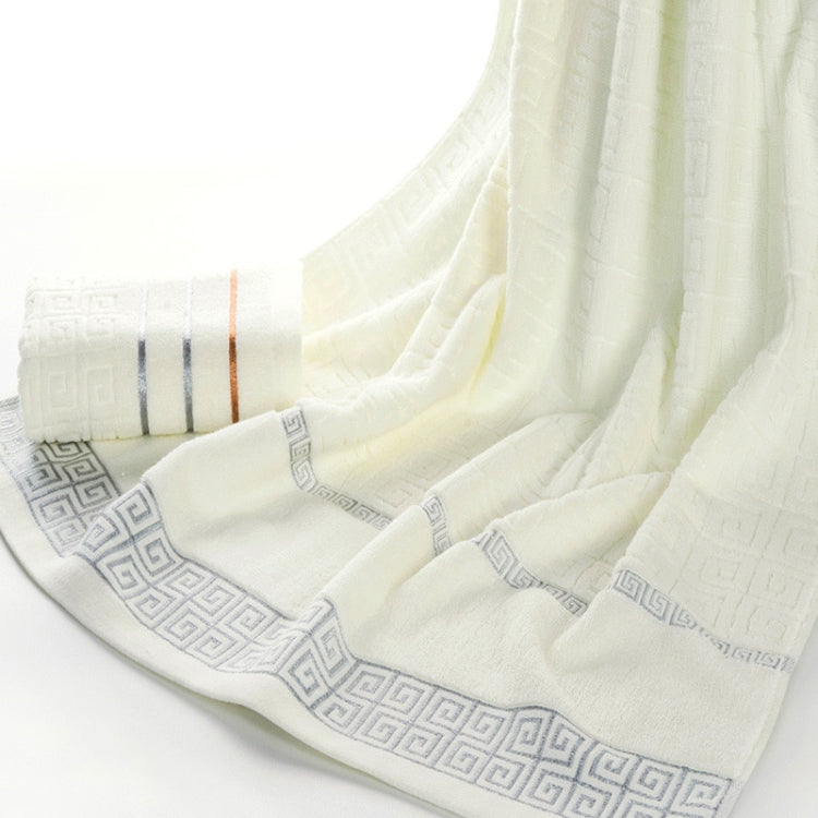 Folded light beige towel with subtle Greek border and pale stripe band detail