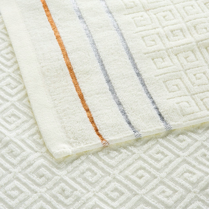 Close-up of light beige cotton towel with orange and blue vertical stripes and embossed weave