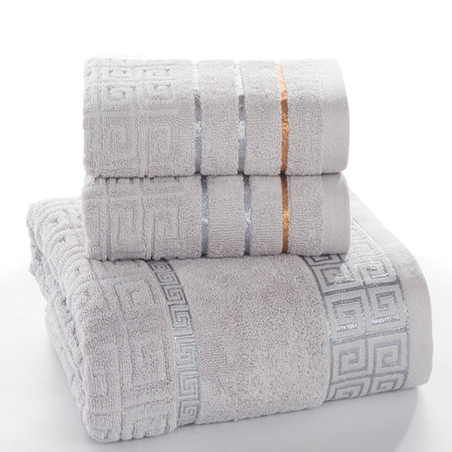 Stacked gray cotton bath towel set with blue stripe bands and Greek key border