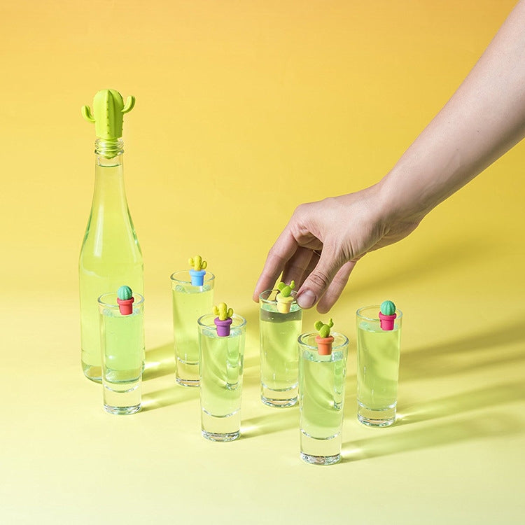 Cactus silicone wine stoppers and glass markers on bottles, with hand placing one