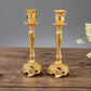 Pair of gold candle holders with decorative pedestal bases and goblet tops
