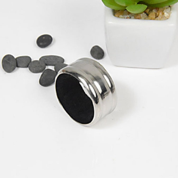 Stainless steel wine stop ring with black opening, scattered metal discs nearby