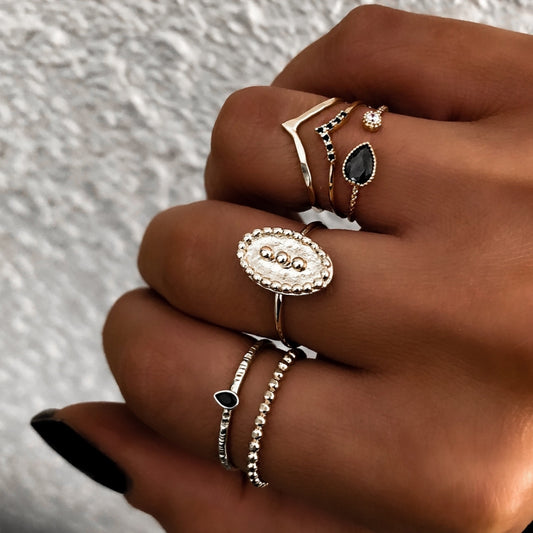 Gold-tone waterdrop and oval rings on hand with black stones and clear details