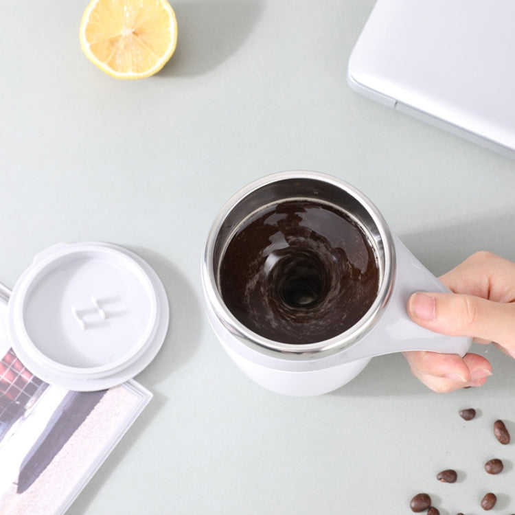 Electric white stirring cup with dark coffee inside and lid placed aside.