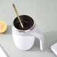 Electric white stirring cup with dark coffee and metal stirrer inside.
