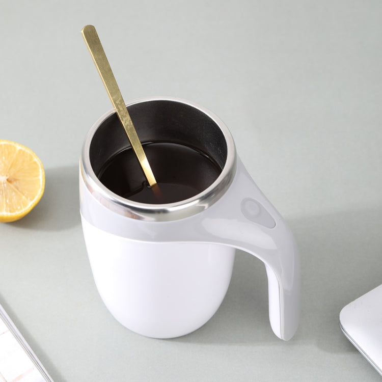 Electric white stirring cup with dark coffee and metal stirrer inside.