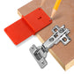 Orange hinge template drilling plate with adjustable hinge hardware on wooden board