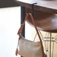 Desktop metal hook stand holding a leather strap bag under a tabletop