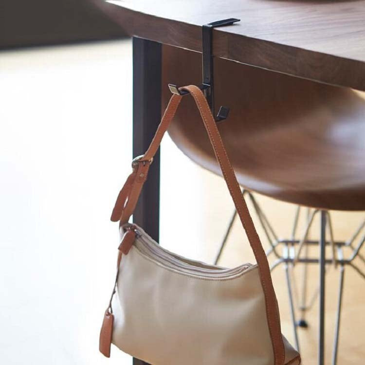 Desktop metal hook stand holding a leather strap bag under a tabletop
