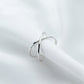 Sterling-silver tone open cross ring on a finger, minimal polished band.