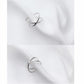 Two views of polished open cross ring on white fabric, slim silver band.