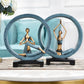 Two blue and gold resin yoga pose statues with seated figures inside matching round rings