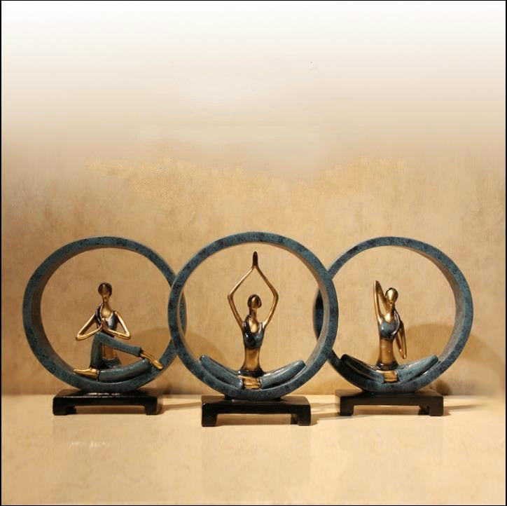 Set of three blue and gold resin yoga pose statues with seated figures on black bases