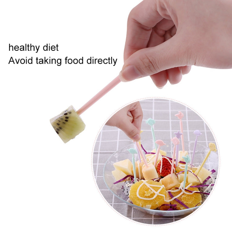 Hand holding pastel cartoon cake fork above fruit salad bowl