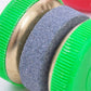 Close-up blue abrasive sharpening stone with green ribbed grip and brass base