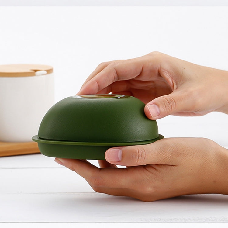 Avocado-green plastic crisper container held by hands with lid closed.