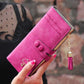 Women’s long zip wallet in bright pink with umbrella button emblem and tassel chain