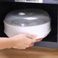Microwave steamer cooker with lid opened, food steaming inside in oven
