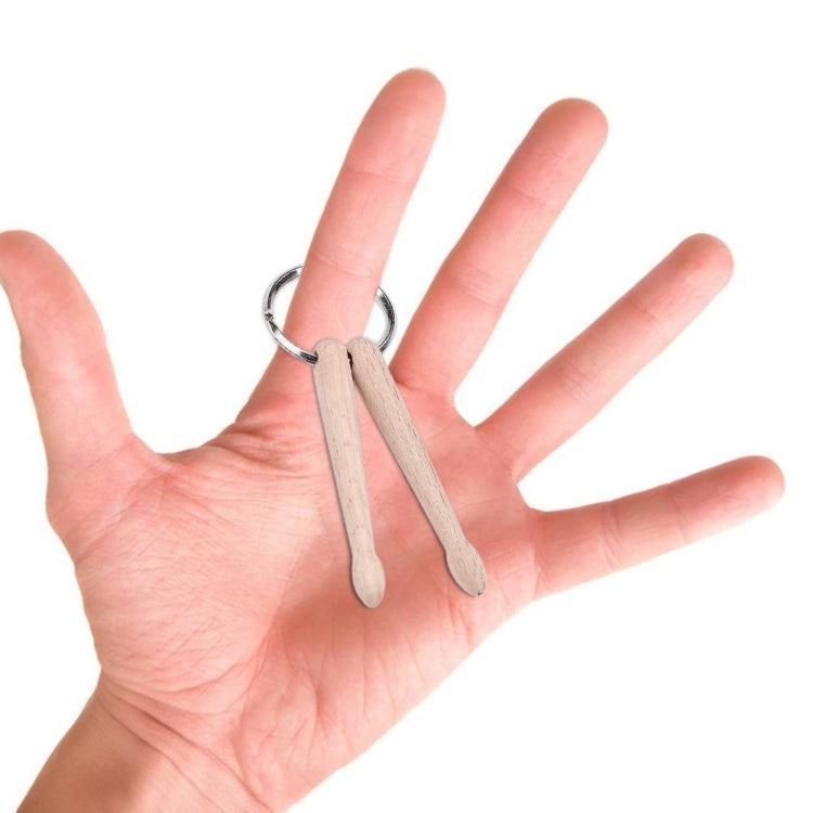 Beech wood mini drumstick keychain held in a hand with silver round ring