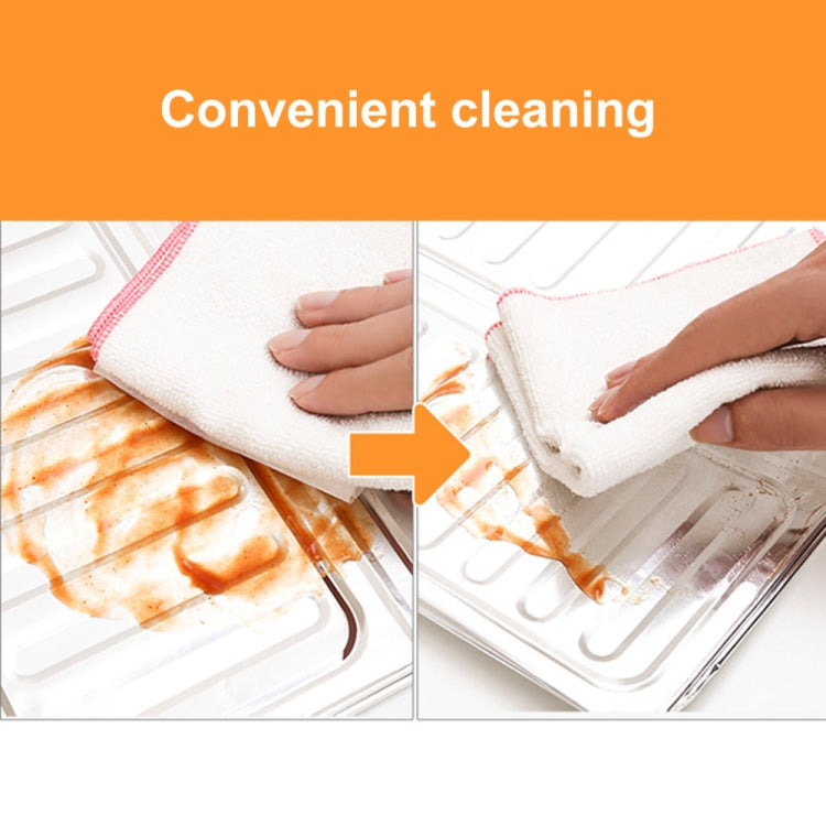 Stainless steel cooktop oil shield with cleaning cloth over grease-splatter area