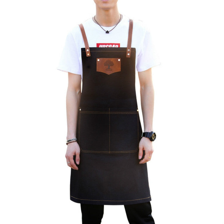 Black hairdressing apron with brown leather straps, front pocket and stitched panels