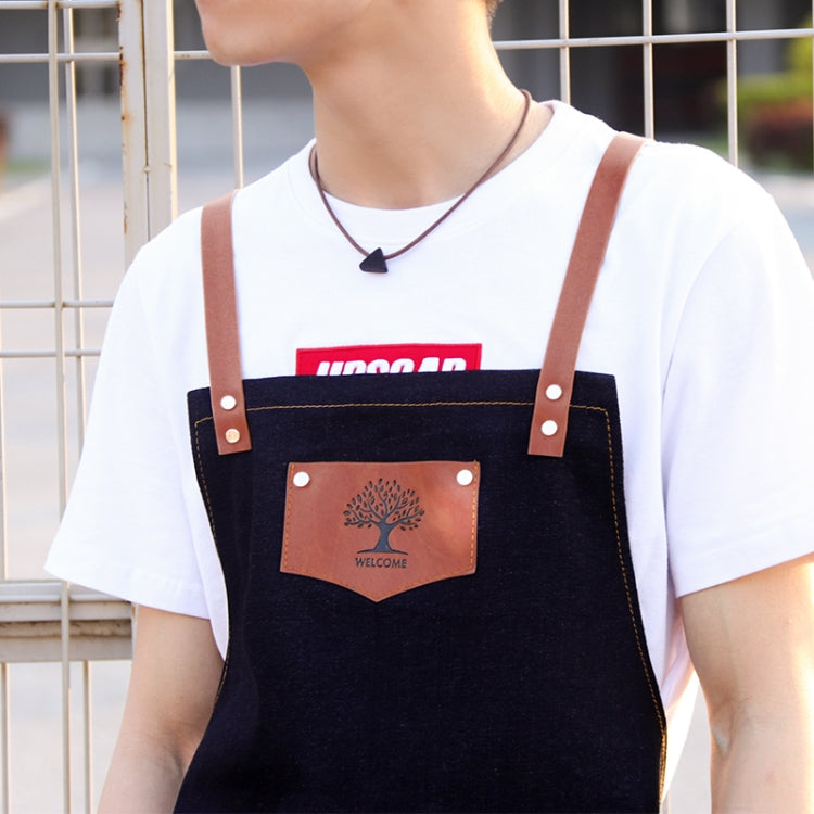Black hairdressing apron chest close-up with brown logo patch and brown leather straps