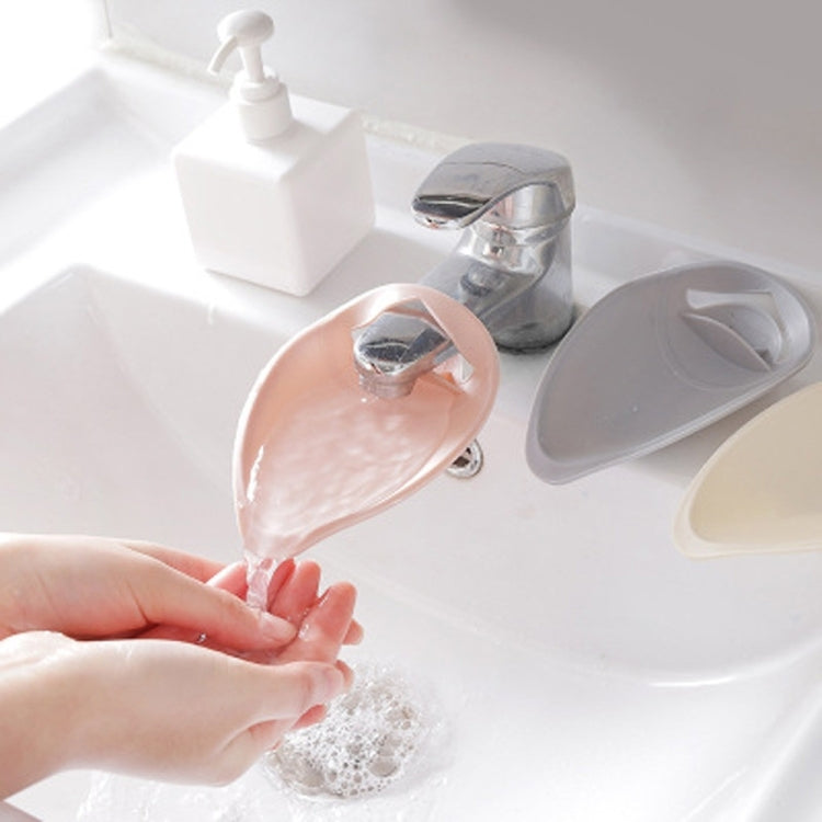 Pink toddler faucet extender installed on sink spout with water directing down