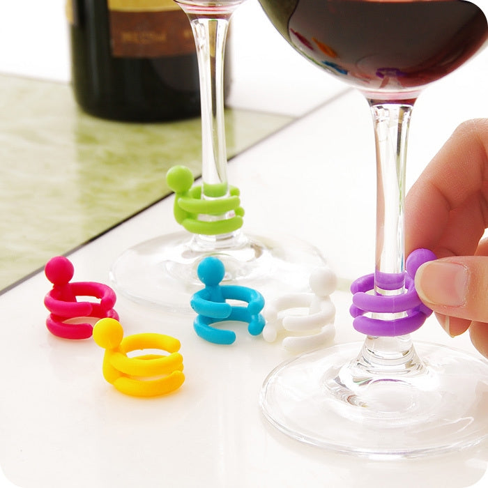 Assorted colorful cartoon silicone spiral wine stoppers on round clear bases, hand inserting one