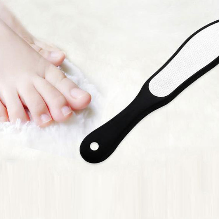 Pedicure foot file with white abrasive surface and black handle, held for use