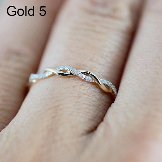 Gold-tone twisted ring with clear stones, worn on a finger
