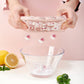 Hands holding a pink animal popsicle mold open with red fruit pieces inside