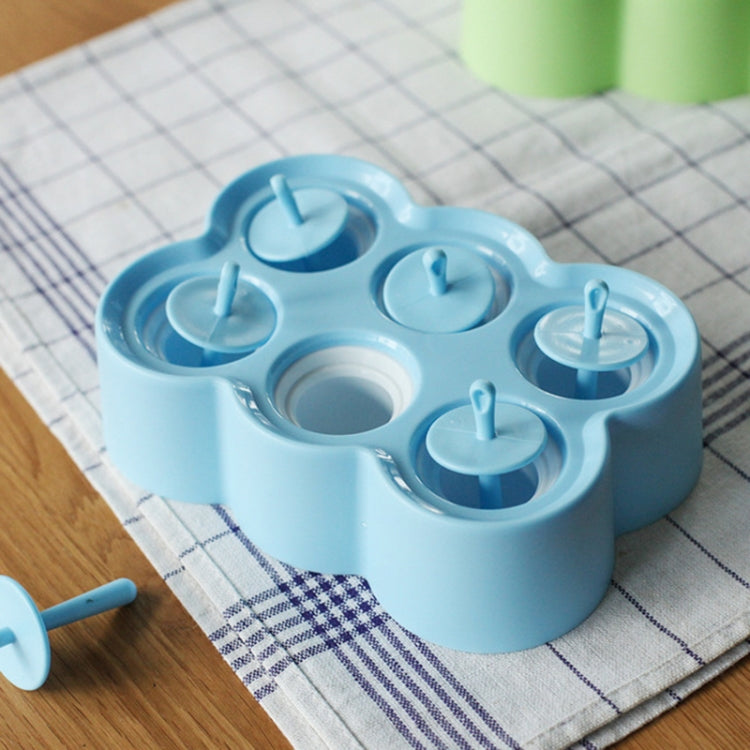 Blue silicone popsicle mold tray with six cup cavities and upright lollipop-style sticks.