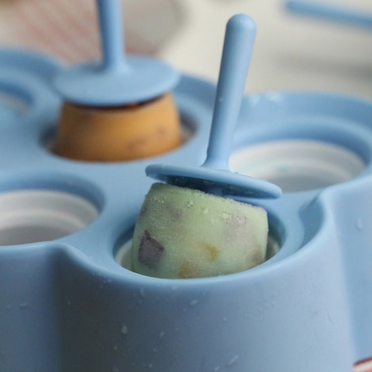 Blue silicone ice mold tray holding a green ice cube with a stick.