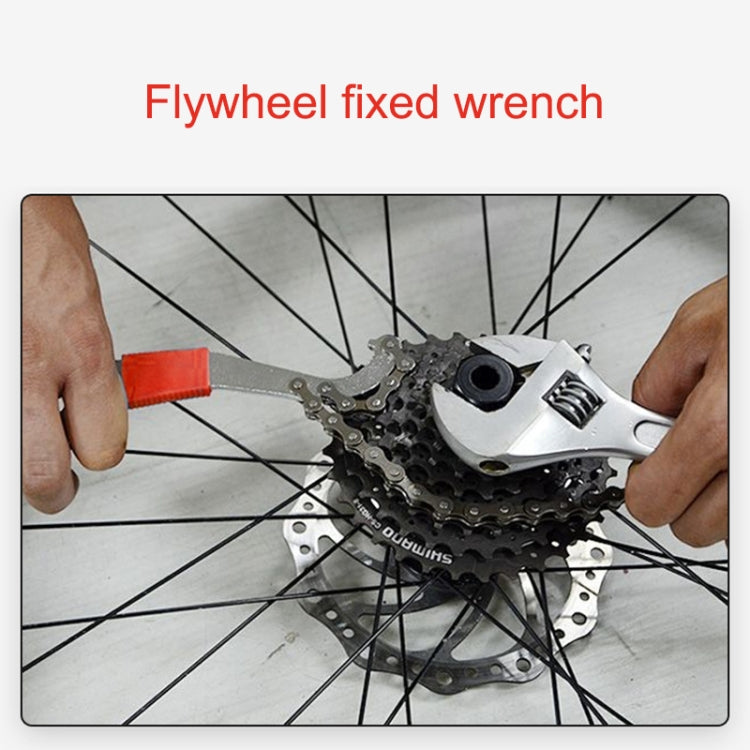 Flywheel fixed wrench tool on bicycle rear wheel, orange-red handle in use