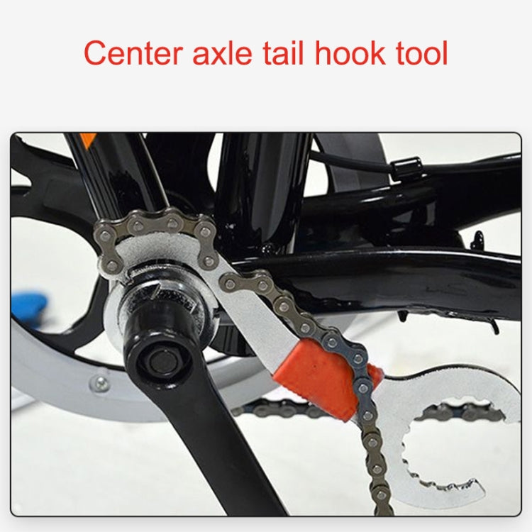 Center axle tail hook tool applied near bike crank and chain, orange-red grip visible