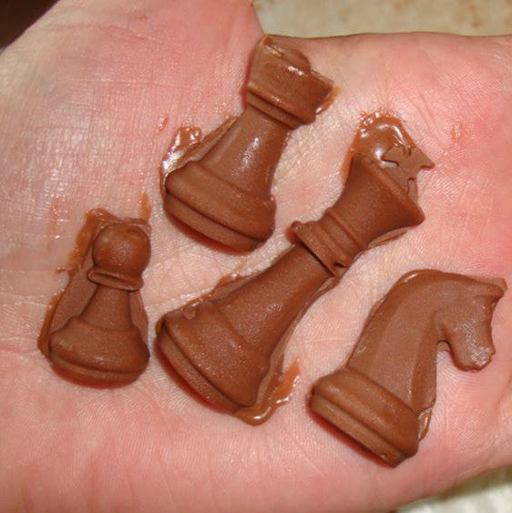 Hand holding molded chess pieces from brown silicone mold