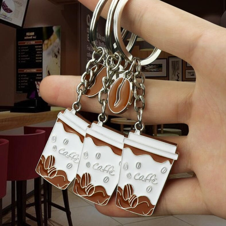 Coffee cup keychains with two white cup pendants, silver chain links, held in hand