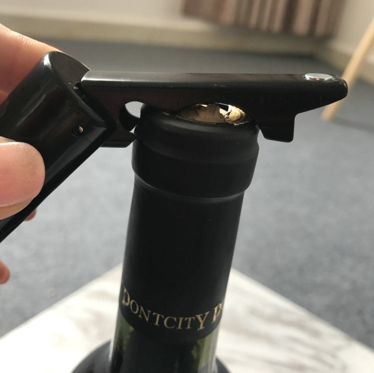 Black corkscrew opener gripping a bottle cork, with red tip visible
