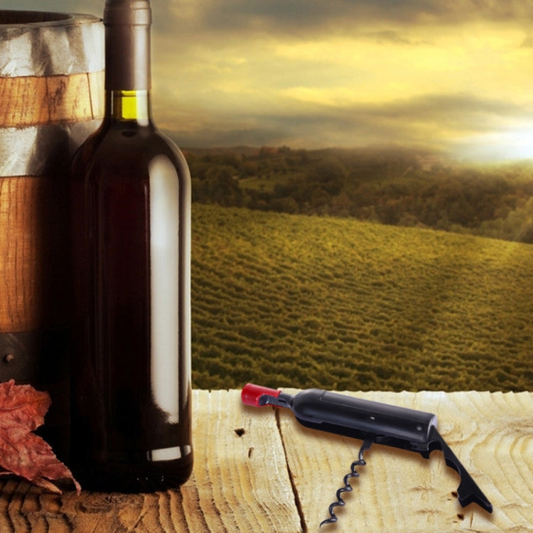 Black and red bottle opener on wood, positioned near a wine bottle